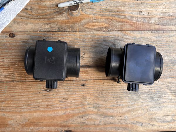 OEM Mazda MAF (left, with blue FS1E identification dot) next to an aftermarket clone (right)